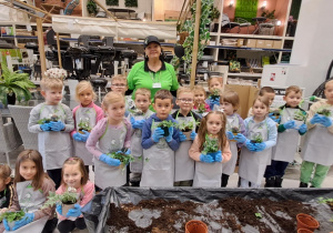 Zdjęcie grupowe z kwiatkami wykonanymi przez z dzieci oraz organizatorką warsztatów.