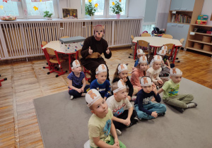 Dzieci z grupy „Misie” siedząc na dywanie pozują do zdjęcia z gościem specjalnym, który ich odwiedził- Pluszowym Misiem.