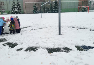 Dzieci toczą ogromną śniegową kulę.