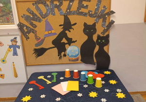 Stolik z przygotowanymi wróżbami i dekoracja andrzejkowa w tle.