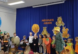 Zdjęcie przedstawia dzieci przebrane za różne owoce, warzywa i zwierzęta, a jedna z dziewczynek przebrana za wróbelka deklamuje swój wierszyk.