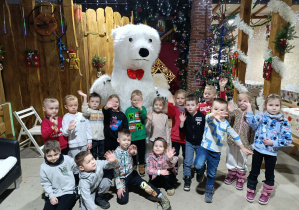 Dzieci z grupy Żabki pozują do zdjęcia z białym misiem.