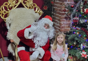 Dziewczynka pozuje do zdjęcia ze Świętym Mikołajem.