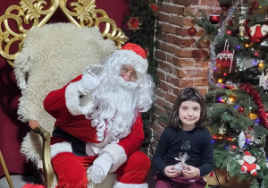 Dziewczynka pozuje do zdjęcia ze Świętym Mikołajem.