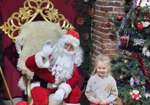 Dziewczynka pozuje do zdjęcia ze Świętym Mikołajem.