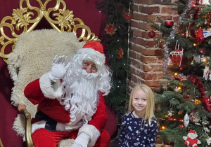 Dziewczynka pozuje do zdjęcia ze Świętym Mikołajem.
