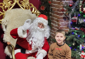 Chłopiec pozuje do zdjęcia ze Świętym Mikołajem.