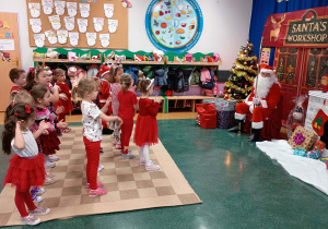 Dzieci stoją przed Mikołajem i śpiewają piosenkę.