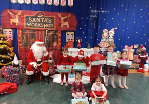 Dzieci pozują do zdjęcia z Mikołajem oraz otrzymanymi prezentami