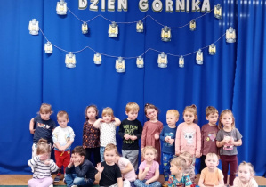 Przedszkolaki pozują do zdjęcia na tle napisu Dzień Górnika.