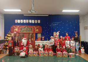 Dzieci z grupy Odkrywcy pozują do wspólnego zdjęcia z Mikołajem i prezentami.