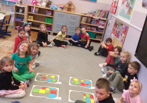 Zdjęcie przedstawia dzieci po posegregowaniu figur geometrycznych ze względu na rodzaj figury geometrycznej.