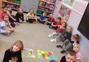 Zdjęcie przedstawia dzieci po posegregowaniu figur geometrycznych ze względu na wielkość.