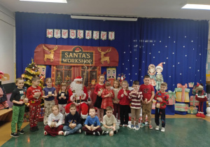 Zdjęcie grupowe przedstawia dzieci stojące wokół Mikołaja