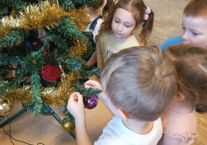 Chłopiec zawiesza bombkę na choinkę