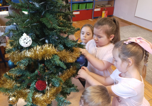 Dziewczynki zawieszają bombki na choinkę