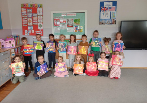 Dzieci z grupy Odkrywcy pozują do wspólnego zdjęcia ze swoimi pracami.