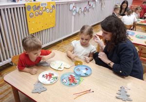 Dwoje dzieci i mama ozdabiają piankowe kształty.