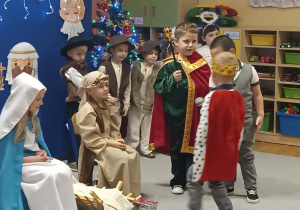 Trzej królowie przynoszą dary i kładą przy żłóbku.