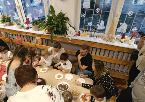 Przedszkolaki wraz z rodzicami ozdabiają pierniki.