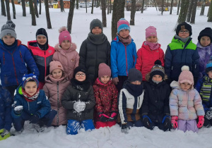 Dzieci pozują do grupowego zdjęcia na śniegu.