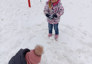 Dzieci lepią kule śniegowe.