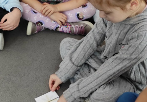 Dziewczynka próbuje dopasować do siebie obrazki przedstawiające dwie połowy śnieżynki.