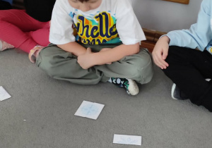 Chłopiec siedzący na dywanie przygląda się ułożonemu przez siebie obrazkowi śnieżynki.