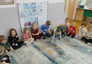 Dzieci siedzą na dywanie.