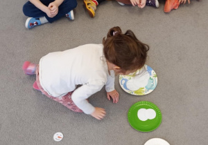 Dziewczynka segreguje koła względem ich wielkości.