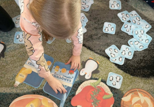 Dzieci wspólnie z nauczycielem grają w grę matematyczną Sardynki dla Kostków