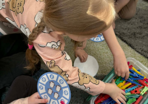 Dzieci przy pomocy klamerek zaznaczają właściwą liczbę pingwinów