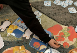 Dzieci wspólnie z nauczycielem grają w grę matematyczną Sardynki dla Kostków