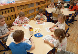 Dzieci z grupy Odkrywcy podczas wykonywania pracy plastycznej z użyciem popcornu.