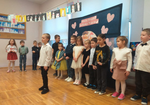 Zdjęcie przedstawia dziecko recytujące wierszyk.