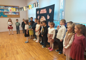 Zdjęcie przedstawia dziecko recytujące wierszyk na tle innych dzieci z grupy Odkrywcy.