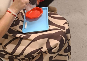 Babcie biorą udział w konkursie i przyszywają guziki do tkaniny.