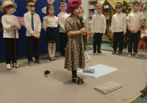 Dziewczynka w czerwonym berecie trzyma mikrofon.