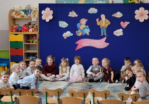 Zdjęcie siedzących na dywanie dzieci z grupy słoneczka, czekających na gości.