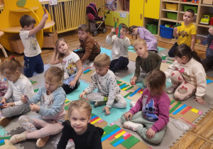 Dzieci siedzą na dywanie, układają klocki NEMI.