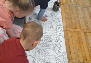Dzieci w skupieniu kolorują kolorowankę.