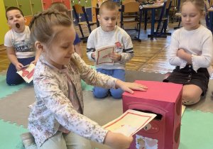 Dziewczynka wkłada kartkę walentynkową do skrzynki na listy.