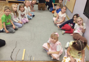 Zdjęcie przedstawia dzieci siedzące przed patykami ułożonymi od największego do najmniejszego.