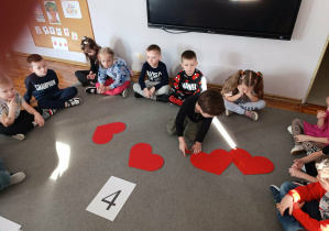Chłopiec z grupy „Misie” odlicza walentynkowe serduszka według wskazanej cyfry.