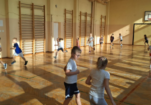 Dzieci biegają w koło sali gimnastycznej.