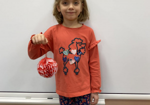 Laureatka konkursu pozuje ze swoją bombką wykonaną z bibuły w kolorze biało – czerwonym.