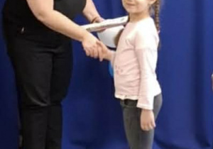 Dziewczynka z grupy Odkrywcy otrzymuje dyplom oraz nagrodę za udział w konkursie.