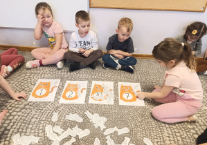 Dzieci karmią kota rybkami.