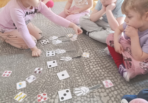 Dziewczynka liczy na kostce, na palcach i układa odpowiednią ilość obrazków