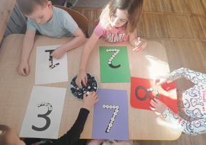 Dzieci układają cyfry z guzików.